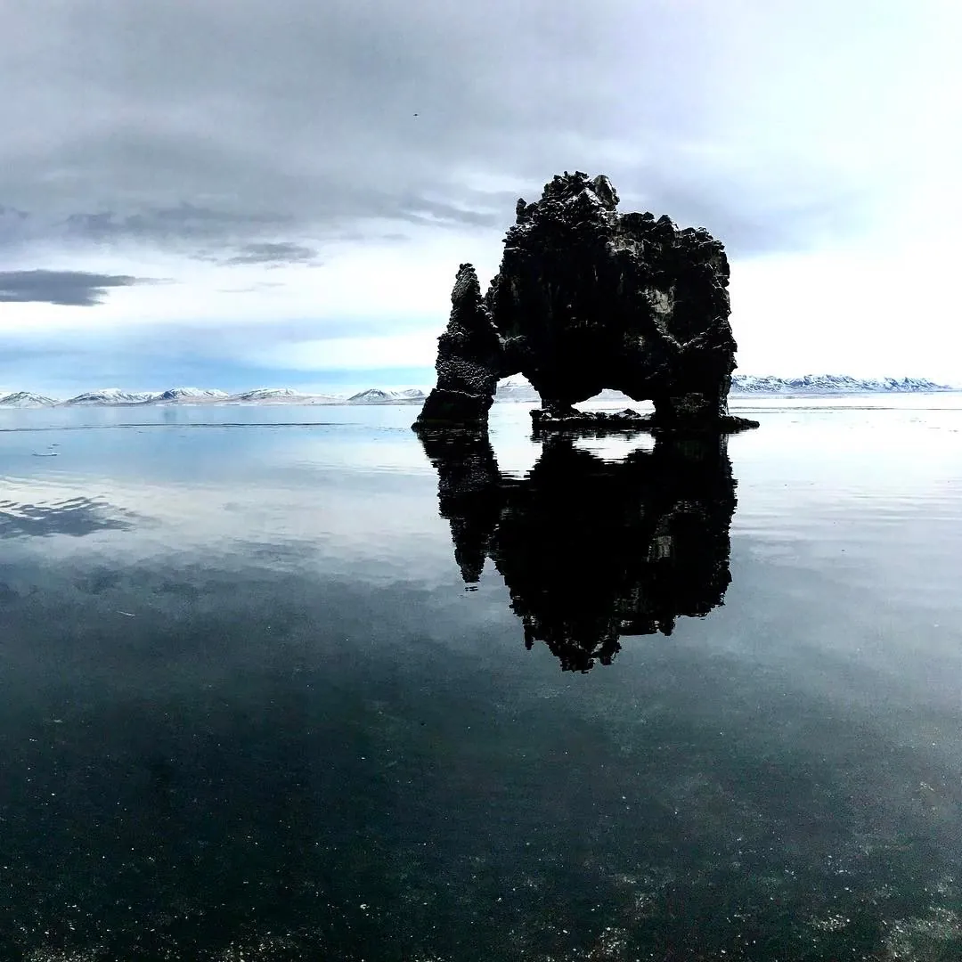 Rocher de Hvítserkur reflété dans l'eau calme